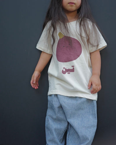 Child wearing a t-shirt with a purple fruit graphic and text against a dark background
