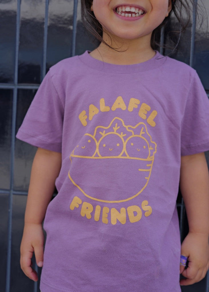 Child wearing a purple t-shirt with 'Falafel Friends' design against a dark background