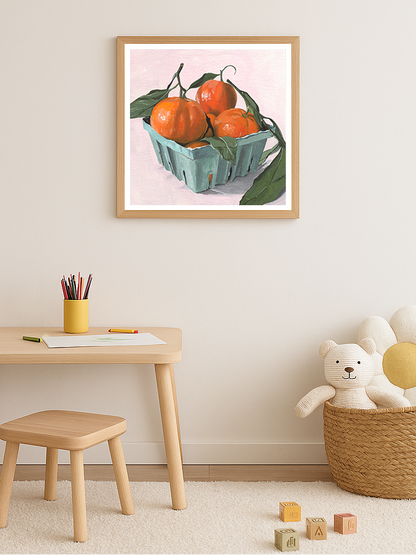 Children's play area with a framed artwork of clementines in a blue carton on a light pink background