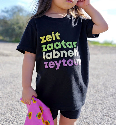 Child wearing a black t-shirt with colorful text outdoors