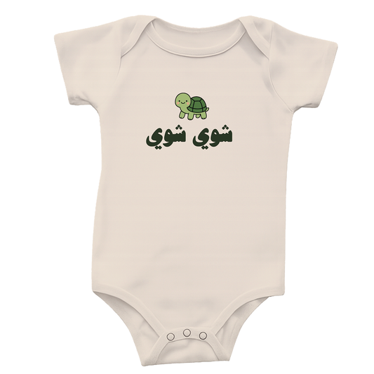 Natural colored baby bodysuit with a green turtle graphic and Arabic text saying "slow slow" on a white background