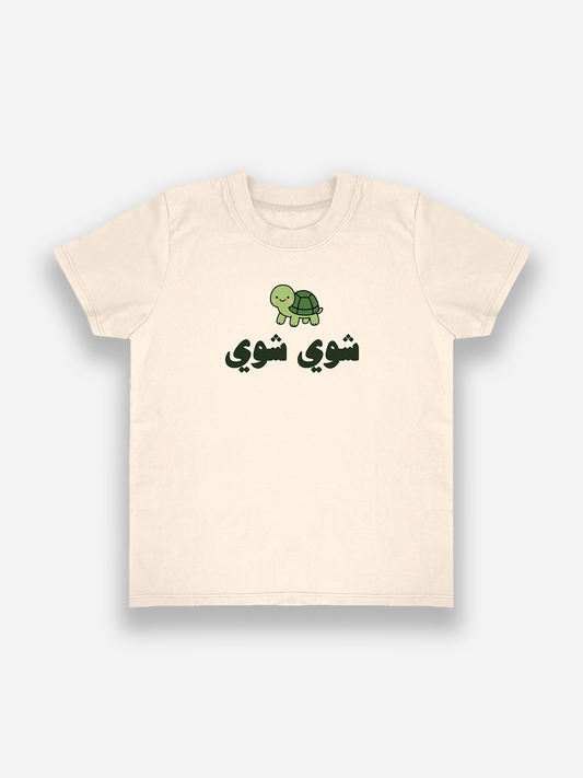 Beige t-shirt with a green turtle graphic and Arabic text on a white background