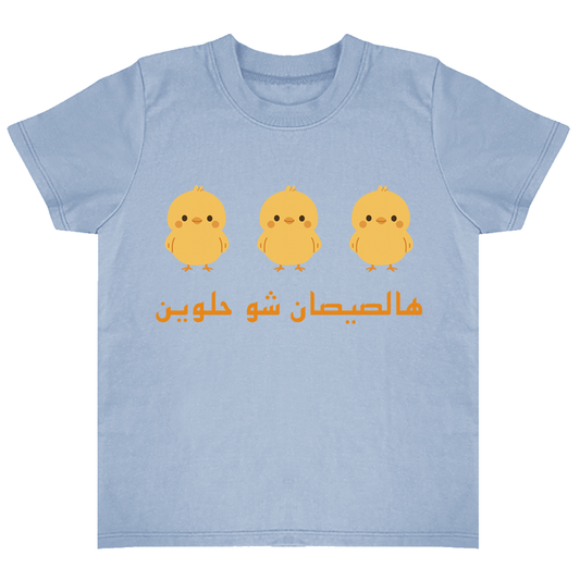 Light blue t-shirt with three yellow chicks and Arabic text on a white background